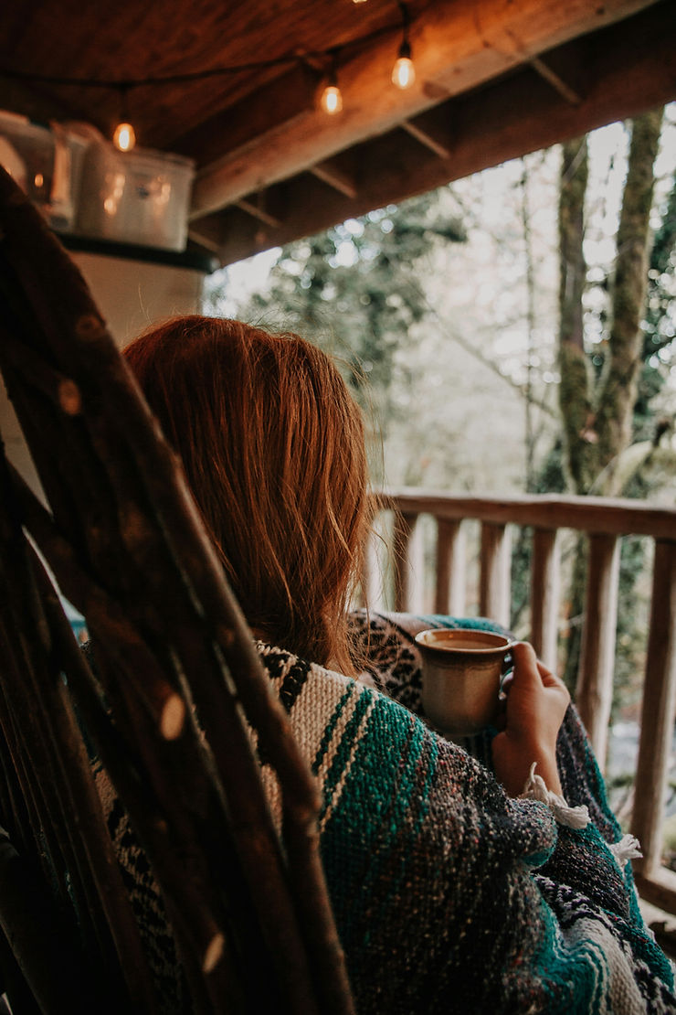 Eine Frau hält eine warme Tasse Tee und hört ihrem Körper zu