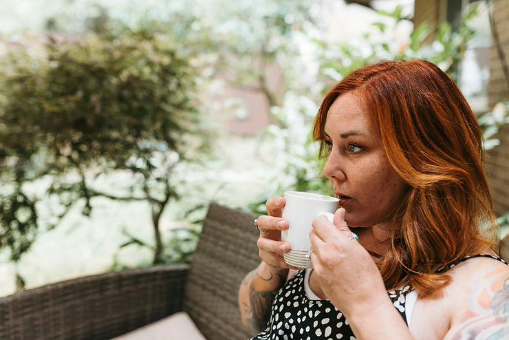 Frau mit einer Tasse Tee im Garten – ein Moment der Ruhe für die Mitte